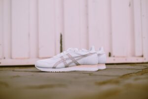 Stylish white sneakers set against a rustic wooden background, perfect for footwear fashion inspiration. - Photo by Hipkicks on Pexels